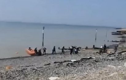 Moment 40 migrants in dinghy land on Kent beach in front of sunbathers